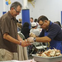 Rotarian Jesus Garcia fills Ray Etchegoin's plate with crab.